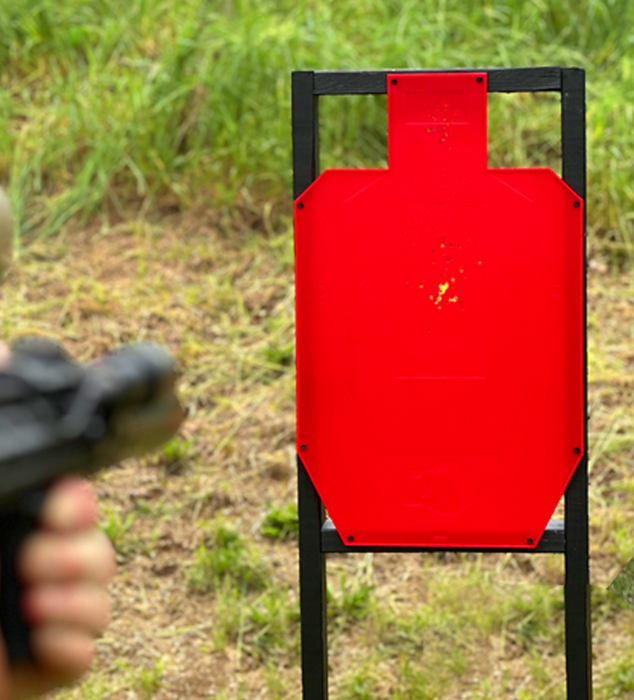 person shooting ar15 at red silhouette shooting target changing color at outdoor shooting range