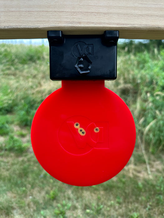 red self healing target mounted upside down used as a swinging target at outdoor gun range 