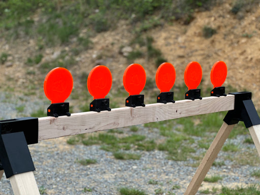 row of bright orange reactive shooting targets mounted to wood at shooting range