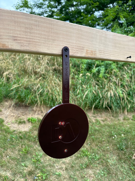 black self healing target mounted to wood with color changing marks from target shooting