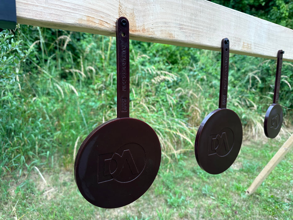 row of black self healing gong targets mounted to wood that are setup for target shooting