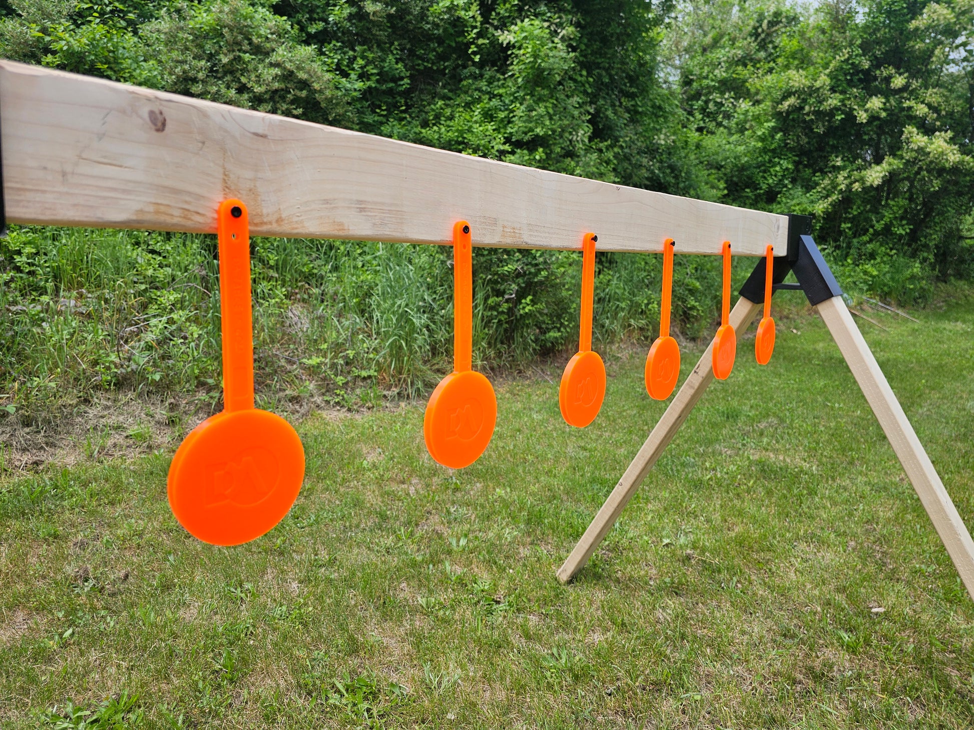 a row of orange self healing gong targets hanging from a wooden rack