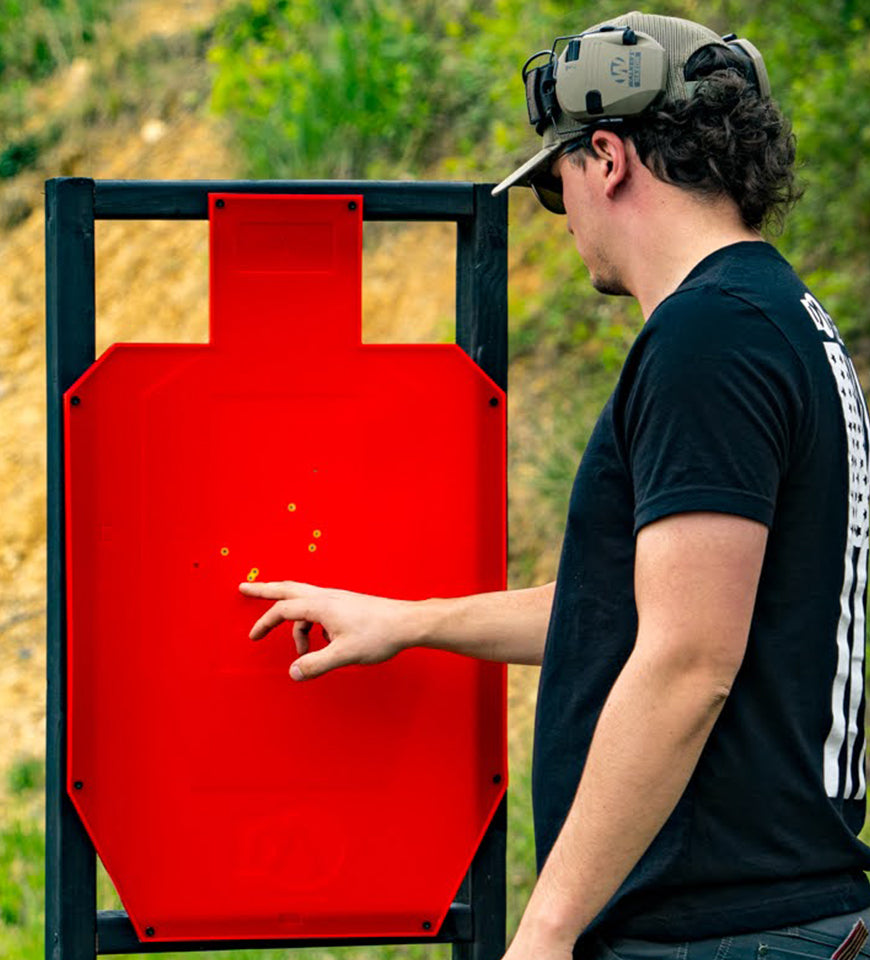 person scoring full size ipsc target at outdoor gun range